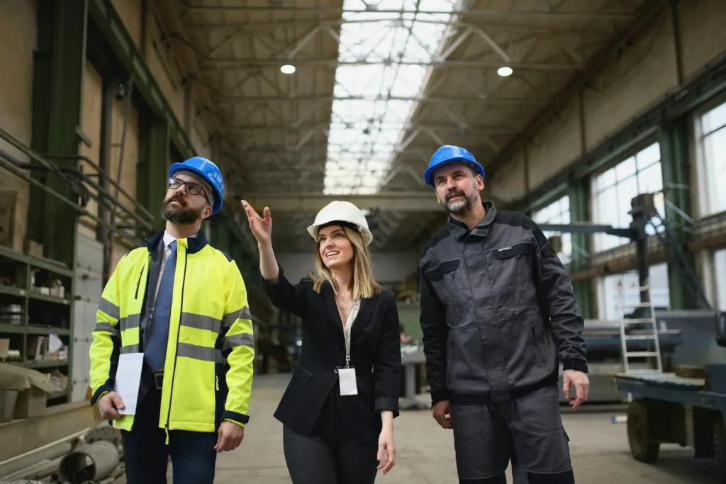Three people wearing hard hats looking around an industrial building