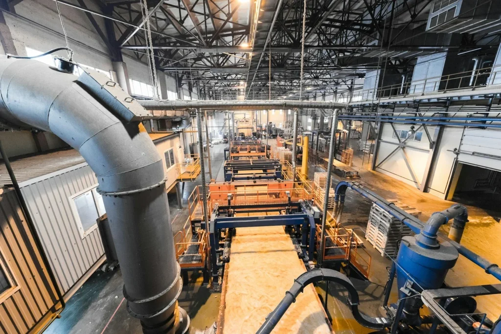 Industrial production floor with processing equipment, overhead utilities, and ventilation ductwork