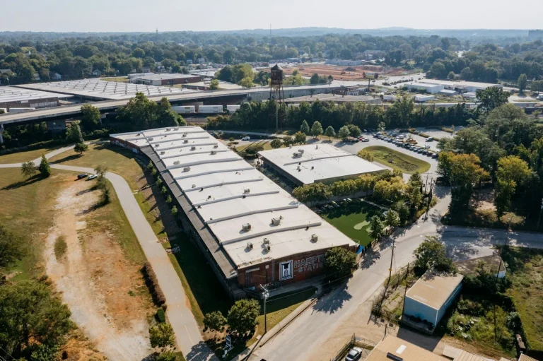 An aerial view of industrial buildings, access roads, and surrounding trees.