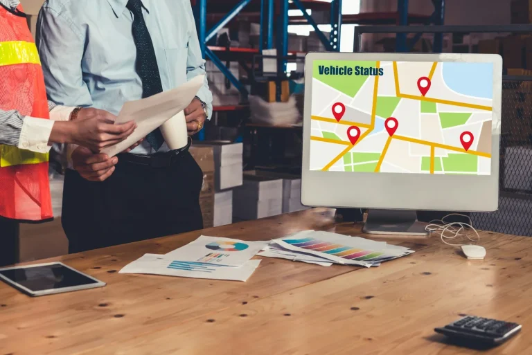Colleagues review documents beside a map display in a warehouse.